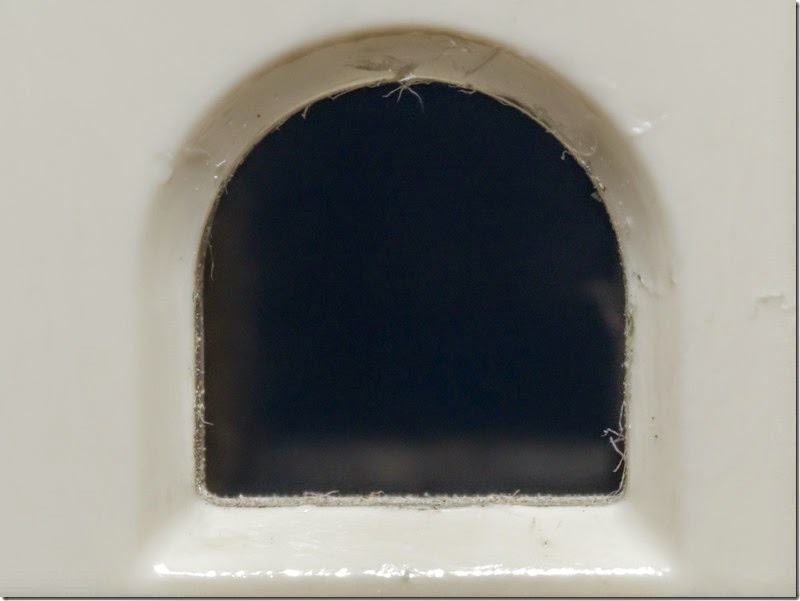 Small rounded-arch opening in white surface, dark interior visible.