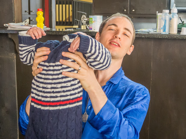Adult in blue lab coat cradles a child in a navy striped sweater in a laboratory with bottles and equipment on the bench.
