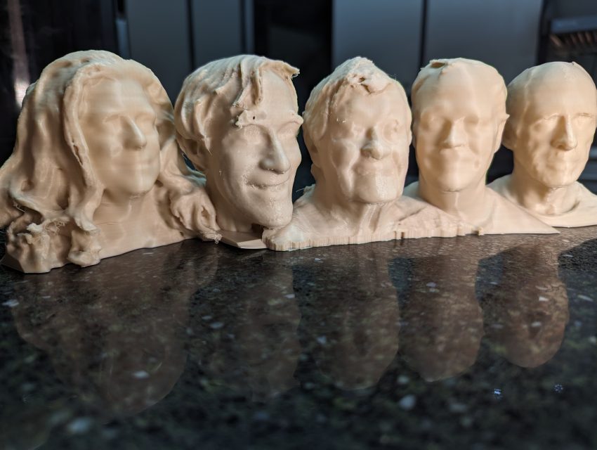 Five beige bust sculptures arranged in a row on a dark glossy countertop; soft lighting with a blue-toned background.